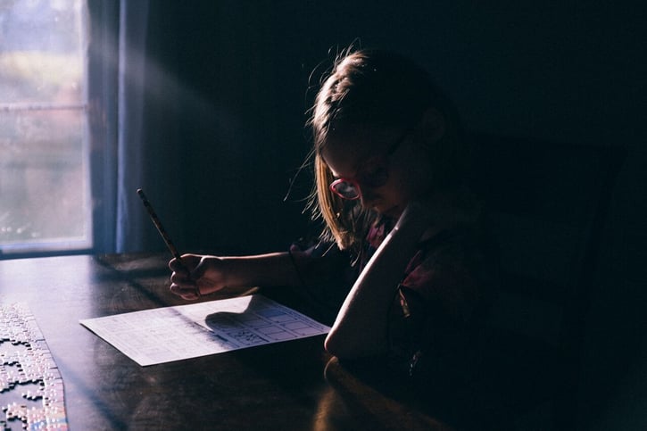A young girl sitting at a dining room table, storyboarding for a book she wrote.